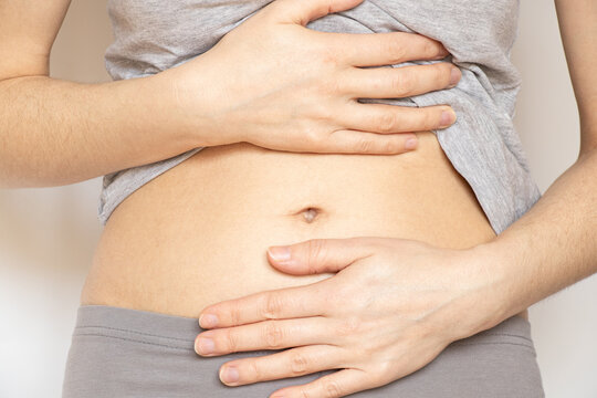 A woman holding her stomach with her hands for topics on abdominal pain, cramps, digestive issues, menstrual pain, bloating