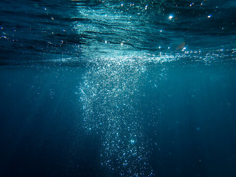 Underwater background with water bubbles and undersea light rays shine. Dark blue ocean surface seen from underwater. Sunbeams and Sea deep or ocean underwater a  Abstract background. sunlight Nature.