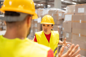 A man and a woman argue passionately while standing in a warehouse full of stock and boxes.