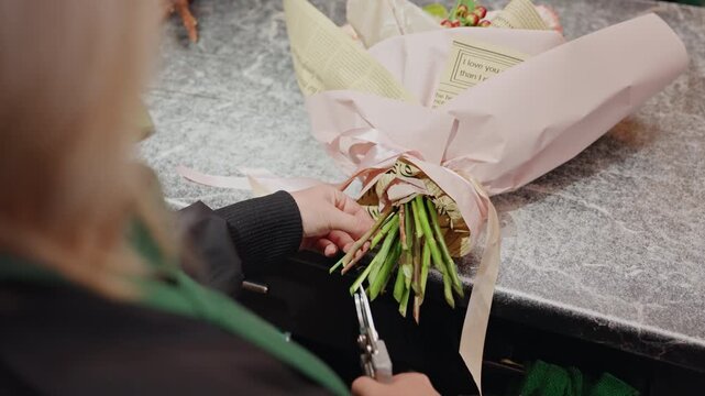White florist tying ribbon around bouquet, securing stems and adjusting paper wrap, gentle hands and pastel flowers, intimate studio light, calm focused motion, final presentation prep