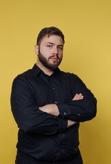 Confident man in black shirt showcasing charisma against a vibrant yellow backdrop