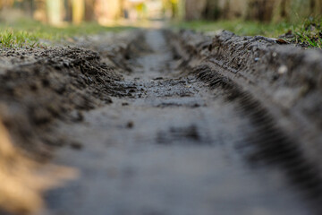 Głębokie koleiny na błotnistej, wiejskiej drodze. Detal śladów opon w mokrej ziemi. Symbol trudnych warunków komunikacyjnych, off-roadu i wiejskiego krajobrazu. © Henryk Niestrój
