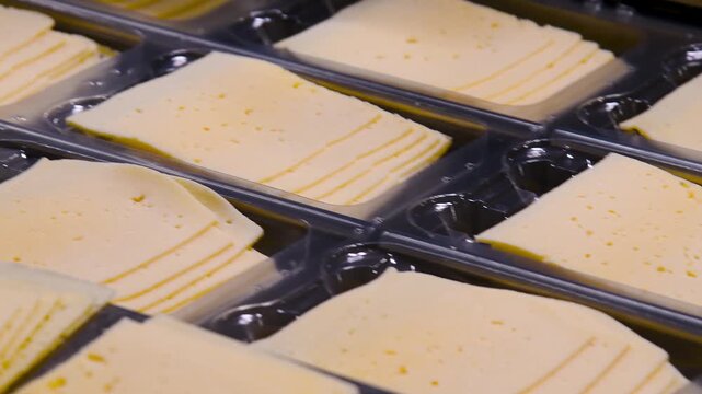 Conveyor belt with pieces of yellow cheese moving on it.