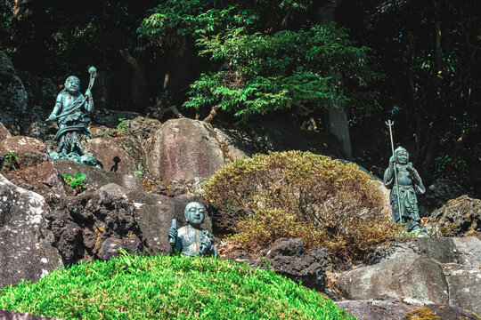 Rock wall of God statues lining a garden of Narita Temple