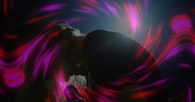 Woman singer stepping forward and raising microphone causing magenta swirls while leading concert