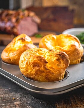 Golden Yorkshire puddings in muffin tin, crispy puffy edges, hollow center, savory baked batter, traditional British side, roasted meat accompaniment, warm lighting.