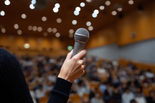 Public speaking event: female speaker with microphone in a lecture hall