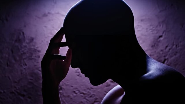 Silhouette of person with hand on head
