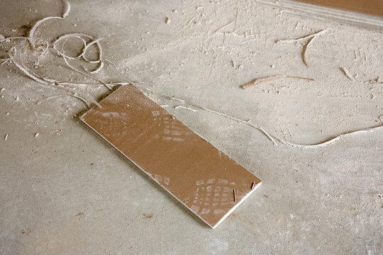 Drywall offcut and gypsum dust on concrete floor after cutting plasterboard panels during interior construction work. Building renovation debris and material leftovers.