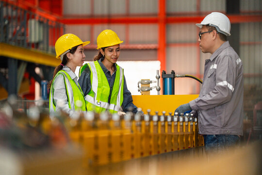 Industrial engineers and supervisor inspecting machine settings on production line in factory, quality control and safety compliance in modern manufacturing industry.