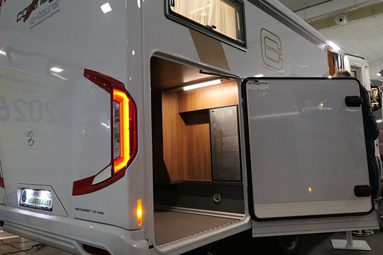Opened spacious rear storage door on modern german camper van vehicle Carthago CT Tourer, displayed on Caravan Bike Travel expo in Nitra, Slovakia, february 2026.  