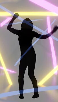 Vertical video: Female silhouette responding to sweeping neon beams performing rhythmic dance poses