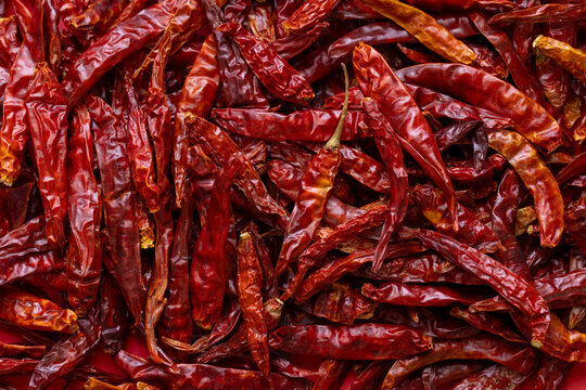 Top view of dried red chili peppers pile background,A close-up, high-angle shot of a vibrant heap of sun-dried red chili peppers. The texture of the wrinkled skin and the deep red color make.
