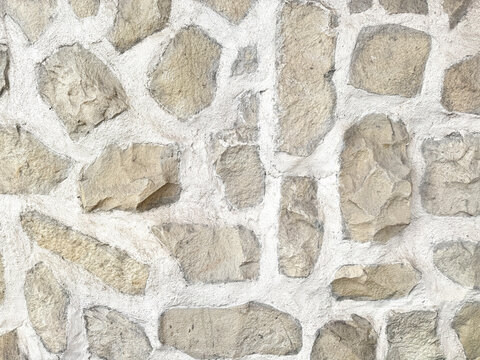 Close up of natural random cut beige yellow cobble stone flattened on a surface. Rough flagstone and gravel stacked randomly and cemented, for floor or wall finishes. Seamless background texture.    