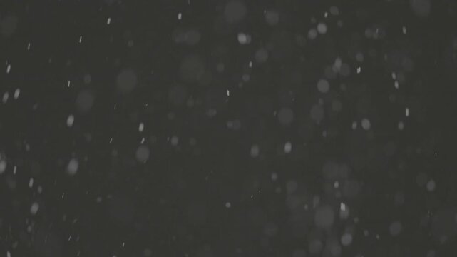 Slow motion falling snow particles on dark background, cinematic winter atmosphere with dense blizzard effect, swirling flakes, bokeh for overlays. ProRes 422, 10 bit ungraded C-LOG2, Slow motion vide