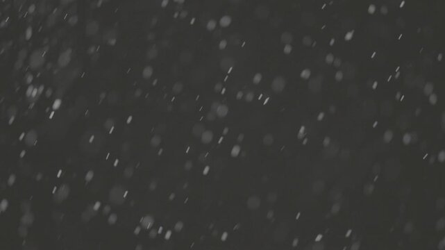 Slow motion falling snow particles on dark background, cinematic winter atmosphere with dense blizzard effect, swirling flakes, bokeh for overlays. ProRes 422, 10 bit ungraded C-LOG2, Slow motion vide