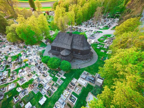 Zabytkowy drewniany kości&oacute;ł św. Barbary w Czarnowąsach z lotu ptaka. Unikalna architektura sakralna otoczona cmentarzem i wiosenną zielenią. Malowniczy element dziedzictwa kulturowego Opolszczyzny.