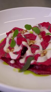 A beautifully crafted colorful ravioli is elegantly plated and garnished. The vibrant colors of the pasta contrast with the rich sauce. High quality FullHD footage