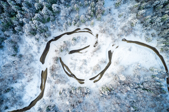 River in winter forest at sunset time, aerial view