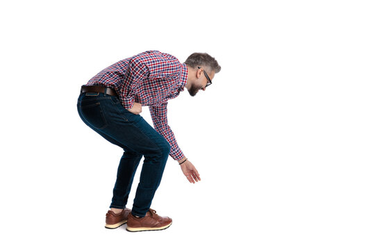 Side view of casual man reaching down for something