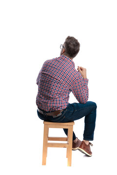 Back view of pensive casual man sitting on stool
