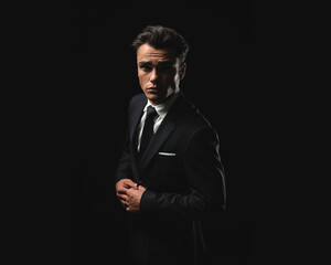 Obraz premium Elegant man fastening suit button while looking forward