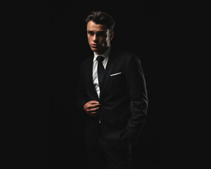 Fototapeta premium Confident young man adjusting suit jacket looking forward