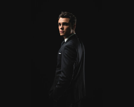 Confident young man in formal suit turning around
