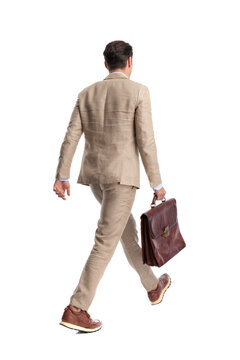 Rear view of stylish man walking away holding briefcase