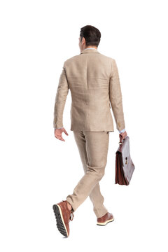 Back view of modern man walking away holding briefcase