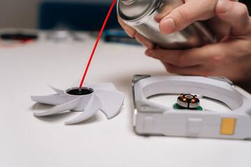 Cropped shot of skilled technician cleaning computer cooling fan components with compressed air...