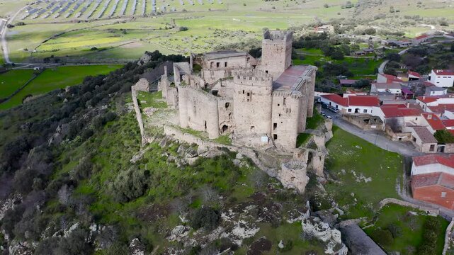 Aerial view of Belv&iacute;s de Monroy Castle, a medieval hilltop fortress ruins overlooking rural Caceres landscape, historic defensive architecture surrounded by countryside and open skies.