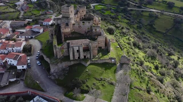 Aerial view of Belv&iacute;s de Monroy Castle, a medieval hilltop fortress ruins overlooking rural Caceres landscape, historic defensive architecture surrounded by countryside and open skies.
