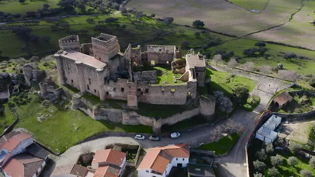Aerial view of Belv&iacute;s de Monroy Castle, a medieval hilltop fortress ruins overlooking rural Caceres landscape, historic defensive architecture surrounded by countryside and open skies.
