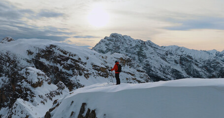 Fototapeta premium Ski mountaineer standing on a snowy cliff in the Dolomites with majestic alpine peaks in the background, capturing winter adventure, solitude and breathtaking mountain scenery.
