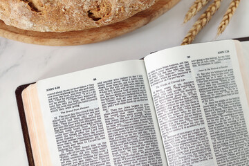 Open holy bible book with loaf of bread and wheat. Top view. Spiritual food and harvest, Christian biblical concept.