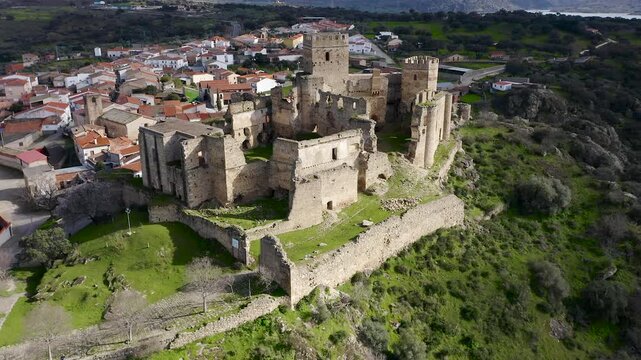 Aerial view of Belv&iacute;s de Monroy Castle, a medieval hilltop fortress ruins overlooking rural Caceres landscape, historic defensive architecture surrounded by countryside and open skies.