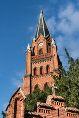 Fototapeta premium Church tower of St. Mary’s Church in Röbel/Müritz, Germany, sunlit facade with blue sky. Historic landmark in Mecklenburg-Western Pomerania.