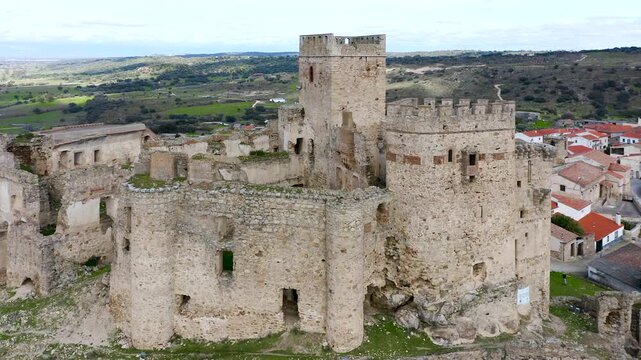 Aerial view of Belv&iacute;s de Monroy Castle, a medieval hilltop fortress ruins overlooking rural Caceres landscape, historic defensive architecture surrounded by countryside and open skies.