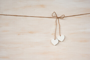 A couple of white hearts hanging against a wooden background