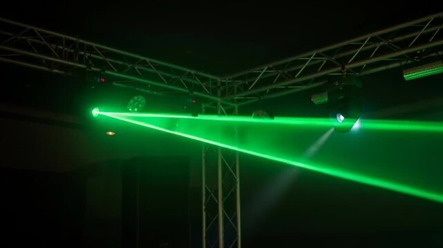 Green laser beam cutting through smoky darkness at a concert or club event