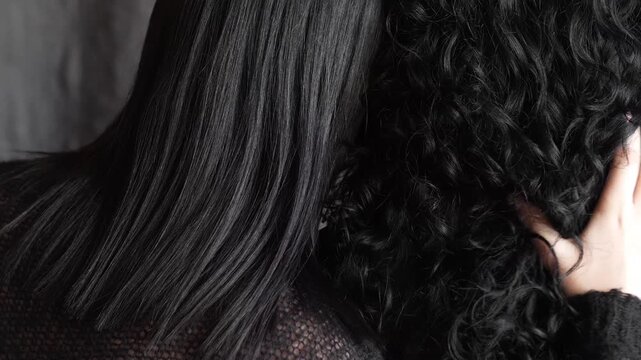 two women with black hair hugging. straight and curly hair view from the back. yin and yang, opposition, before after, keratin hair straightening, curls, curls, biowave. hairdressing services