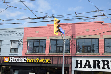 Obraz premium exterior building facade and signs of Pat's Home Hardware and Harry's Charbroiled, a fast food restaurant, located on Coxwell Av north of Gerrard St E, Toronto