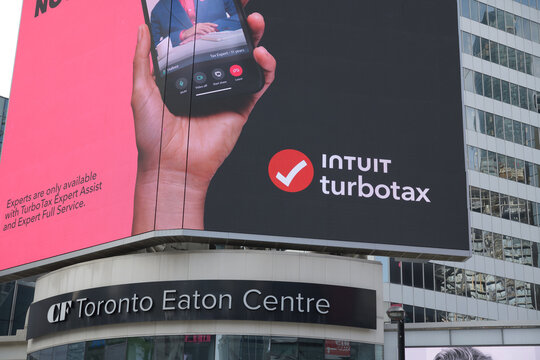 wide view of digital billboard advertising for Intuit with catchy slogans above entrance to CF Toronto Eaton Centre, facing Sankofa Square