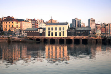 Obraz premium Cityscape of Gijon with Waterfront Buildings and Reflections at Daytime. Asturias, Spain.