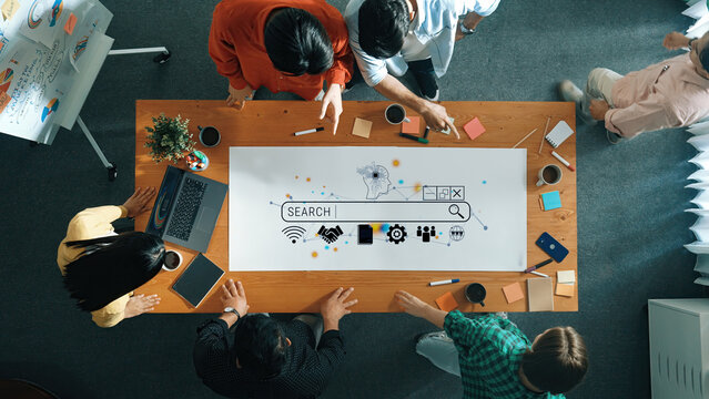 Diverse Group Collaborating on Digital Ideas Around a Table Featuring Search Interface and Creative Tools for Project Development Quark.