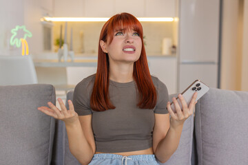 Young woman at home checks smartphone gets bad news sighs after game loss and failed bet looks so...