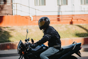 A male motorcyclist wearing a helmet on a city motorcycle in the city in summer