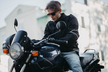 A man motorcyclist wearing sunglasses in the city in summer on a motorcycle