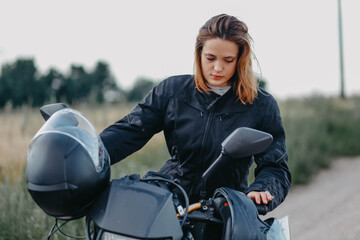 A woman sits on an enduro motorcycle in a field in nature